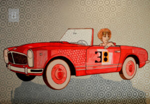 Obraz akrylowy Michała Wareckiego. Na pierwszym planie widzimy elegancki, czerwony kabriolet w stylu retro, który nosi numer 38. Za jego kierownicą siedzi młoda kobieta o rudych, modnie ostrzyżonych włosach, wpatrzona w coś poza kadr. Jej poza jest swobodna, a mina zamyślona, co nadaje postaci intrygującą głębię.