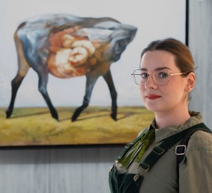 Galeria Wiele Sztuki, zdjęcie malarki Agnieszki Lewandowskiej do profilu artystki na stronie Galerii na tle jednego z jej obrazów.