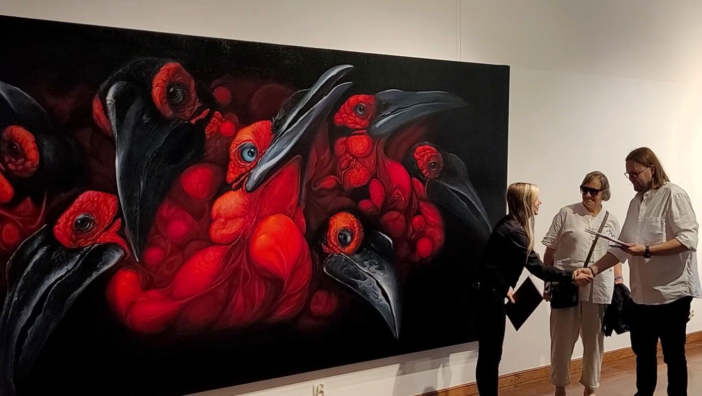 Galeria Wiele Sztuki, artystka Barbara Kuchnowska odbiera dyplom pod odczytaniu recenzji dyplomu. W tle fragment obrazu pod tytułem "2178" przedstawiającego grupę dzioborożców, egzotycznych ptaków zagrożonych wyginięciem. Akademia Sztuk Pięknych w Gdańsku, czerwiec 2023. 