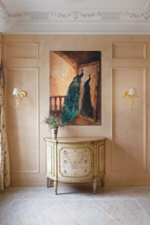 Galeria Wiele Sztuki, wizualizacja w pomieszczeniu obrazu akrylowego autorstwa ukraińskiej malarki Khrystyny Hladki przedstawiającego pawia, siedzącego na drewnianej poręczy w pokoju z lustrem i żyrandolem.