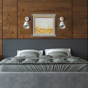 Zdjęcie przedstawia wizualizację wiszącego na ścianie obrazu autorstwa Bożeny Paluch pod tytułem „Brzeg”. Praca powstała w 2023 r. w czasie XII Kazimierskiej Pleneriady Uczelni Artystycznych i jest zainspirowana urokliwymi widokami Kazimierza nad Wisłą. Widzimy na niej nagrzany słońcem brzeg obmywany falami rzeki. Obraz przy ograniczonej palecie jest pełen subtelnych niuansów kolorystycznych, które nadają mu delikatności i liryzmu oraz podkreślają kontrast pomiędzy fakturalnymi kamieniami a gładką taflą wody.