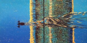 Zdjęcie przedstawia podwójny obraz (tzw. dyptyk) pod tytułem Kilwater (inaczej ślad na wodzie). Obraz został namalowany w technice akrylowej przez Jacka Malinowskiego, znanego polskiego współczesnego artystę. Obraz przedstawia pejzaż, którego centralnym elementem jest tytułowy kilwater, czyli ślad pozostawiony przez płynącą po wodzie kaczkę. Kilwater jest przedstawiony w sposób abstrakcyjny, jako dynamiczna, wirująca masa kolorów. Cała paleta kolorystyczna tej pracy jest utrzymana w chłodnych odcieniach błękitu i turkusu, kontrastujących z ciepłymi tonacjami żółci i pomarańczy, które symbolizują światło słoneczne odbijające się na powierzchni wody. Obraz dostępny w Galerii Wiele Sztuki.