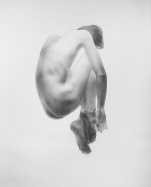 Na zdjęciu jest rysunek na papierze przedstawiający leżący akt męski. Skulona sylwetka mężczyzny z kolanami podciągniętymi pod brodę zdaje się leżeć na niewidocznym podłożu. Praca jest dostępna w Galerii Wiele Sztuki.