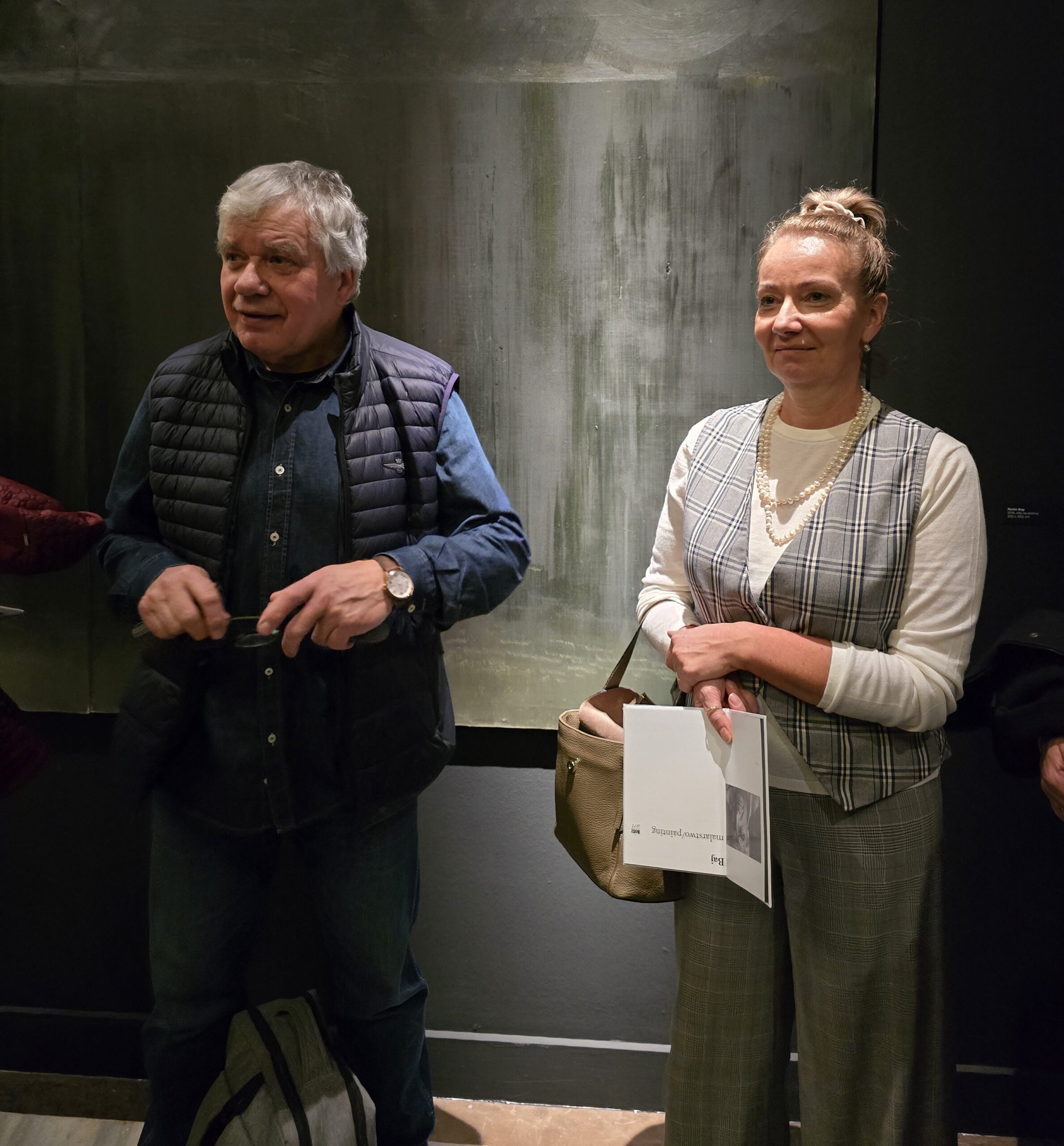 Zdjęcie prof. Stanisława Baja z Elą Kraszewską podczas autorskiego oprowadzania po wystawie artysty, Warszawa, Galeria Opera, 28 listopada 2024. 