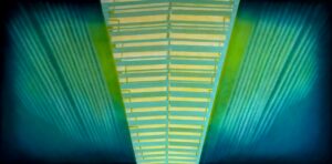 Obraz Jakuba Łącznego „Terminal”, współczesna abstrakcja industrialna, symetryczna kompozycja z centralnym świetlistym trapezem i rytmicznymi zielono-błękitnymi promieniami, akryl na płótnie, dostępny w ofercie Galerii Wiele Sztuki.